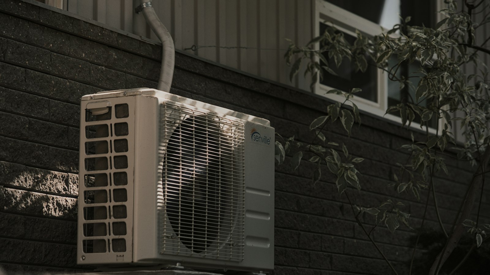 A white air conditioner sitting on top of a brick wall