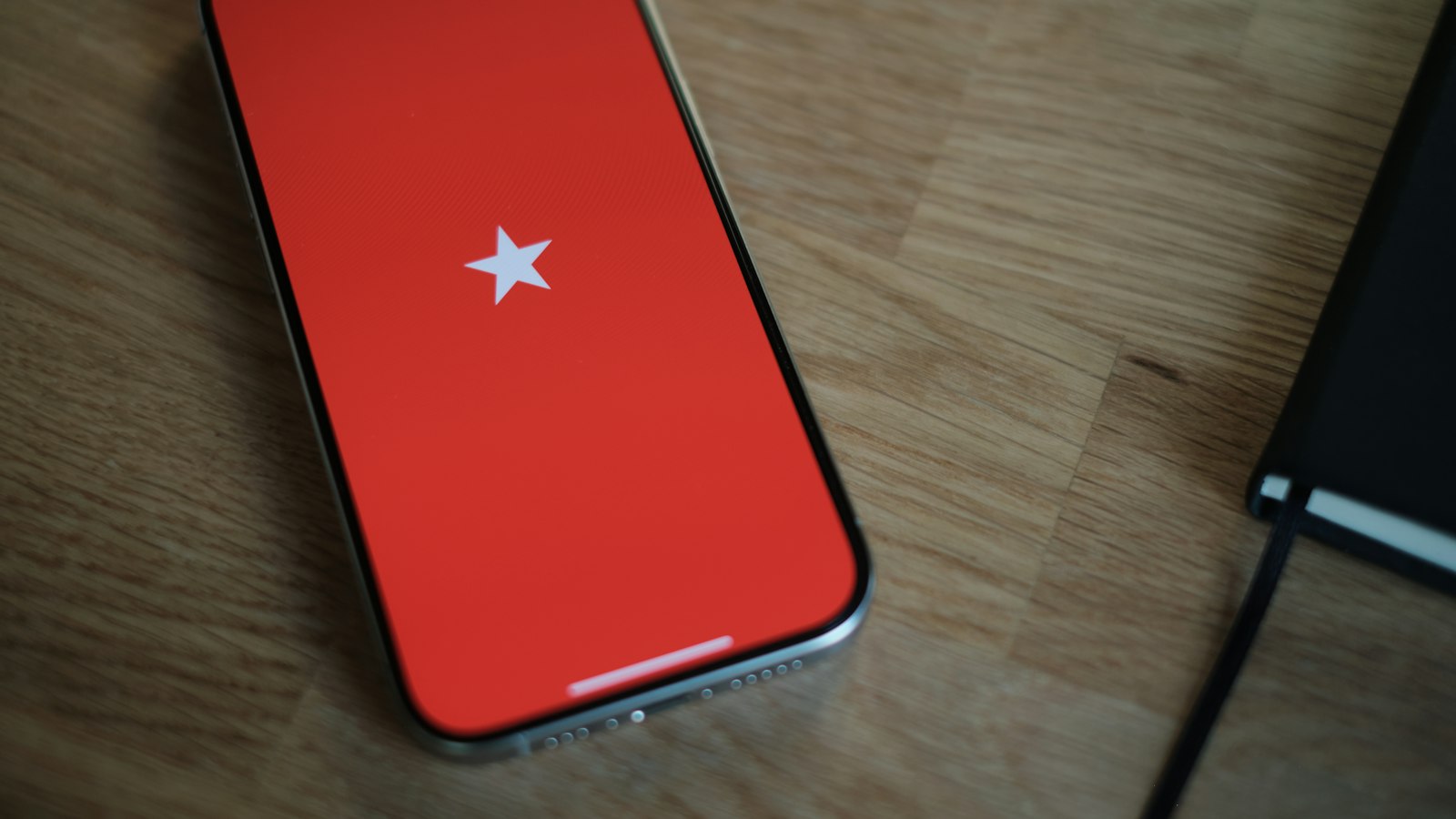 A red cell phone sitting on top of a wooden table