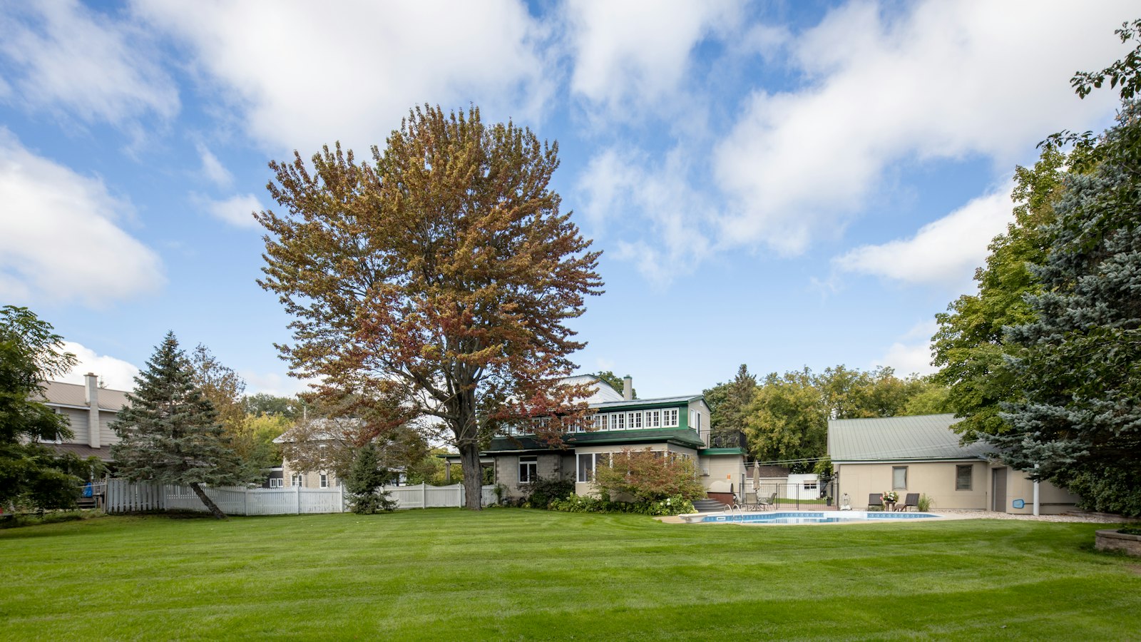 A large yard with a pool and a house in the background