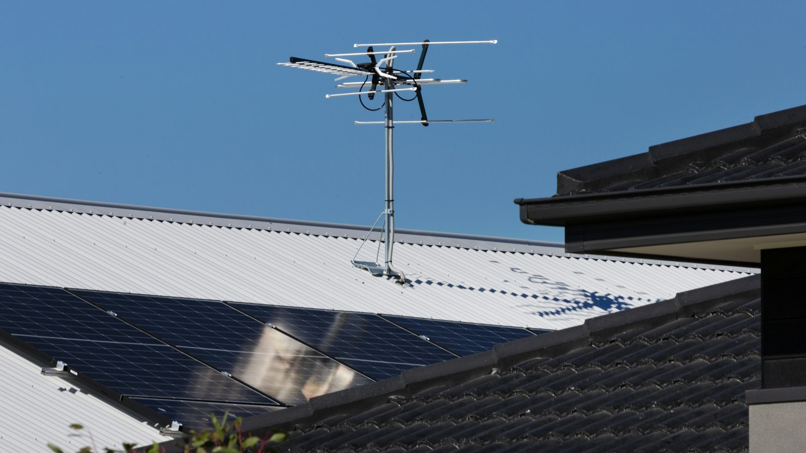 A television antenna stands tall against a clear blue sky