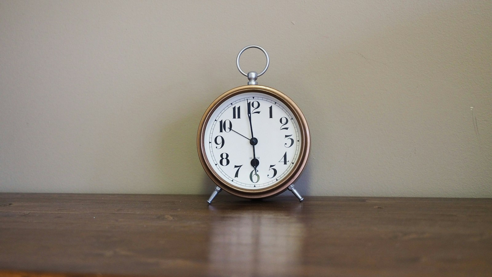 A vintage alarm clock sits on a wooden surface